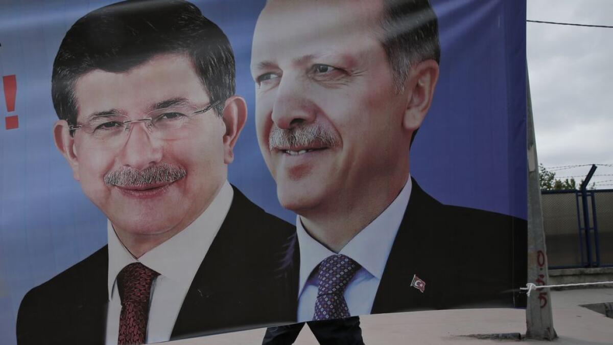 A man walks past a poster with pictures of Turkish Prime Minister and leader of the AKP party Ahmet Davutoglu, left, and Turkeys President Recep Tayyip Erdogan and the partys former leader,  in Istanbul. 