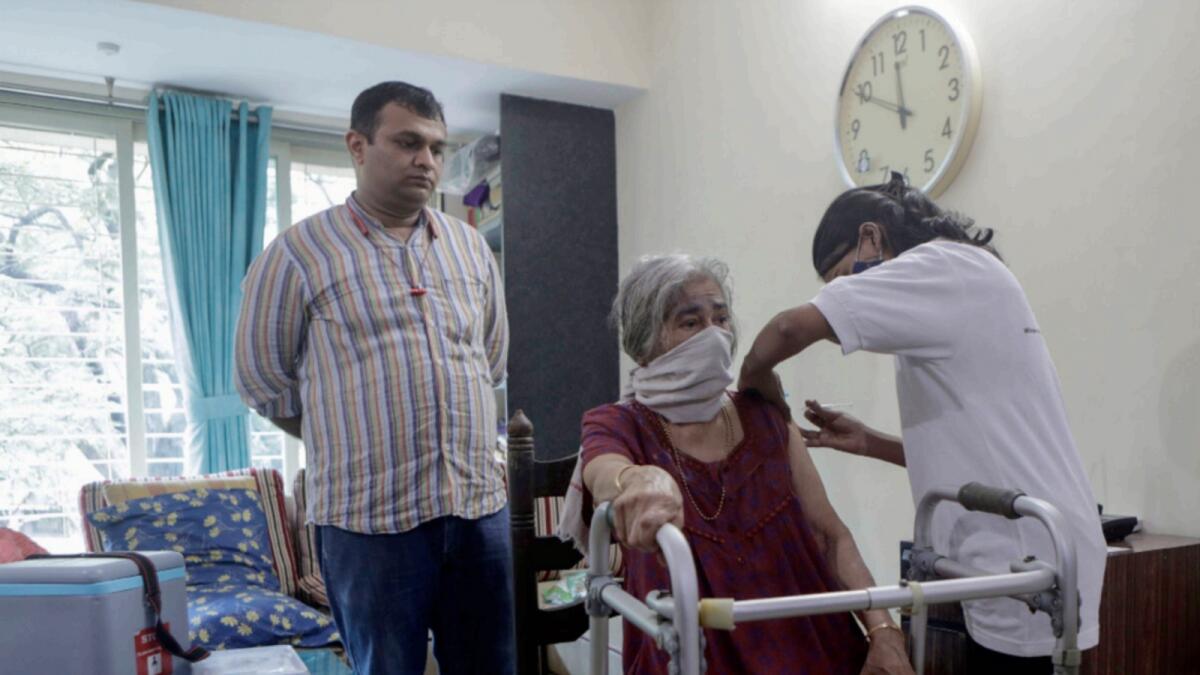 A health worker administers Covid-19 vaccine to an elderly woman who has difficulty in moving around inside their house during a door to door vaccination programme in Mumbai. — AP
