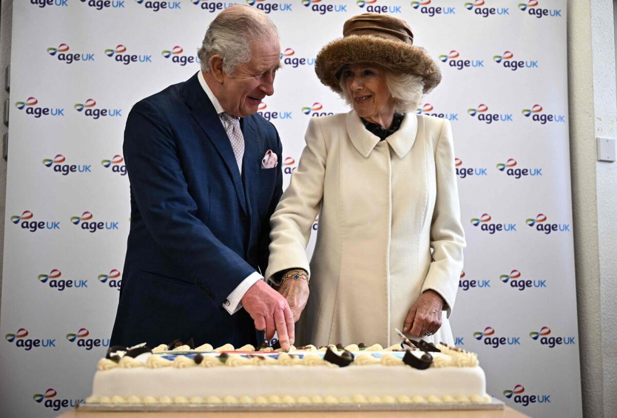 Britain's King Charles III and Britain's Camilla, Queen Consort cut a cake during an afternoon tea with volunteers and service users of the charity organisation Age UK at the Colchester Library during a visit in Colchester. — AFP file
