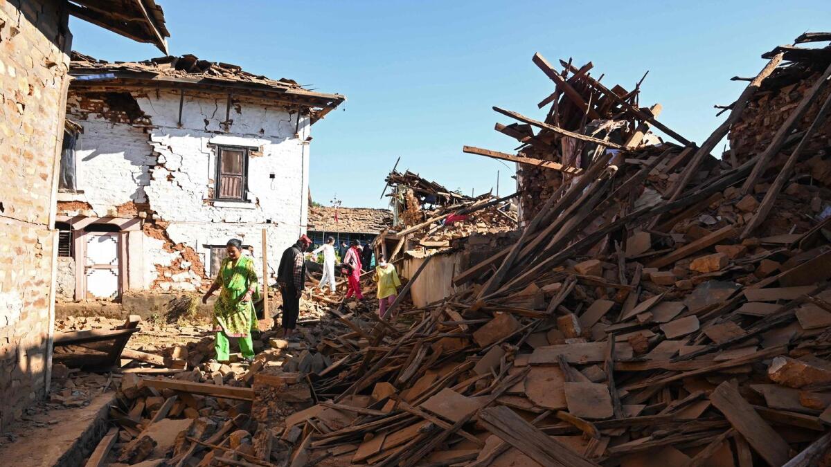 People walk through ruins of houses in the aftermath of an earthquake at Jajarkot district on November 4, 2023. AFP