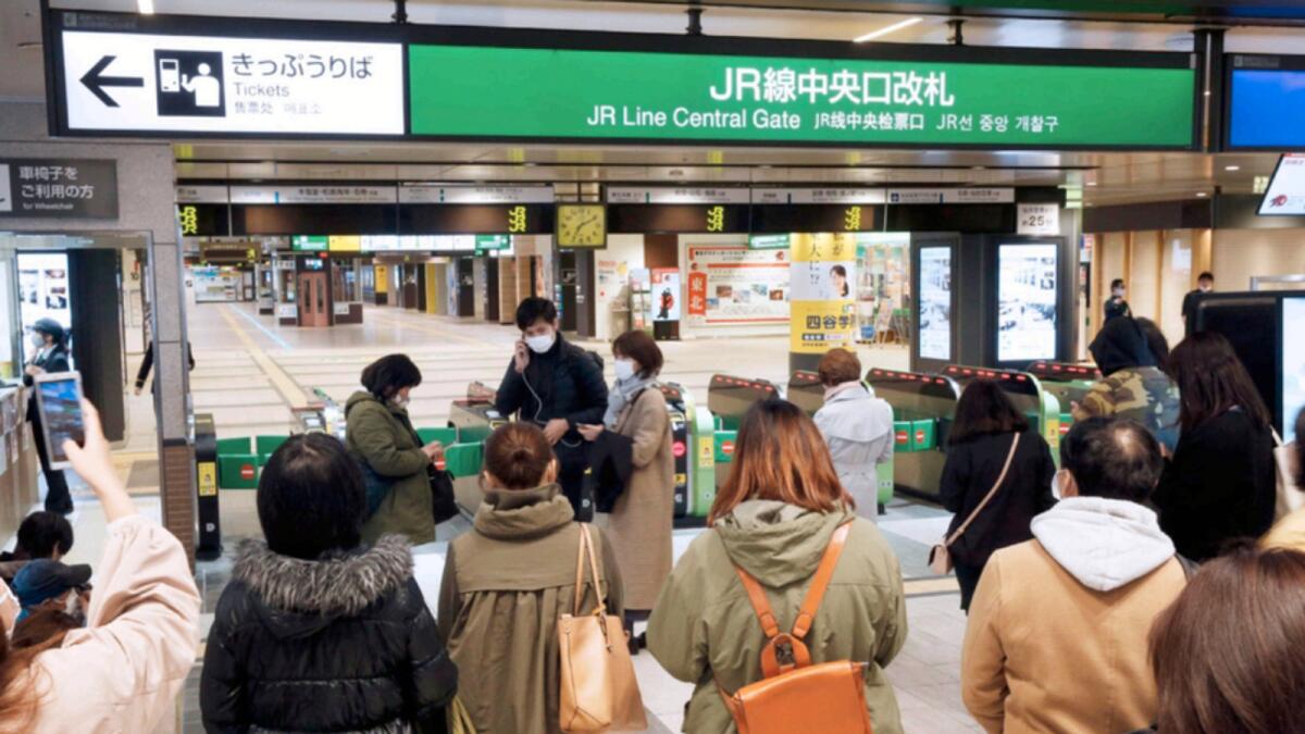 People gather in front of a ticket gate at a station as train services are suspended following an earthquake in Sendai on Saturday. AP