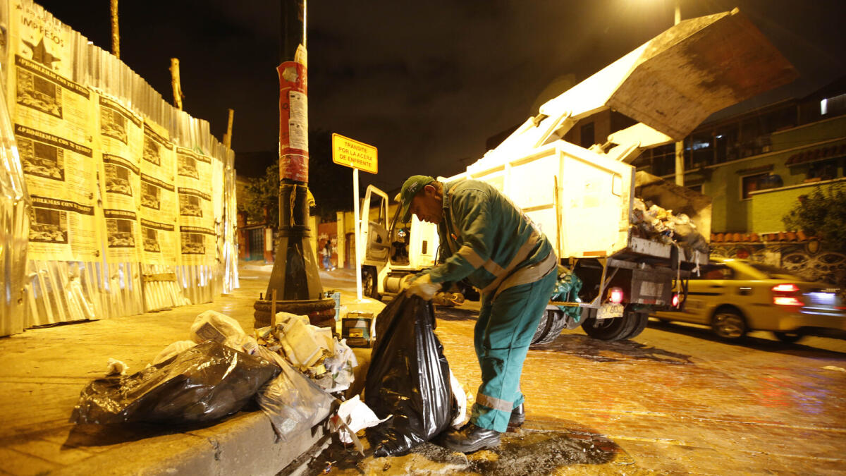 Garbage truck driver Jose Alberto Gutierrez searches for books in the trash, in Bogota, Colombia.