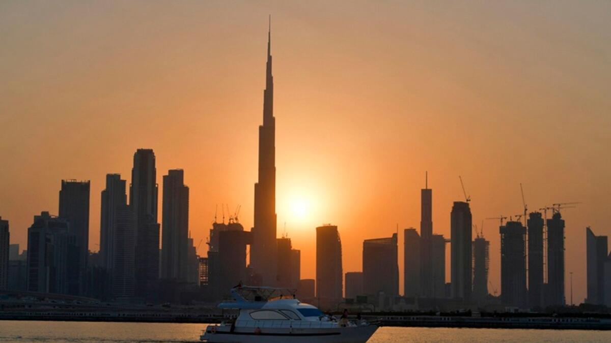 The sun sets behind Burj Khalifa and other high rise buildings in Dubai. — AFP