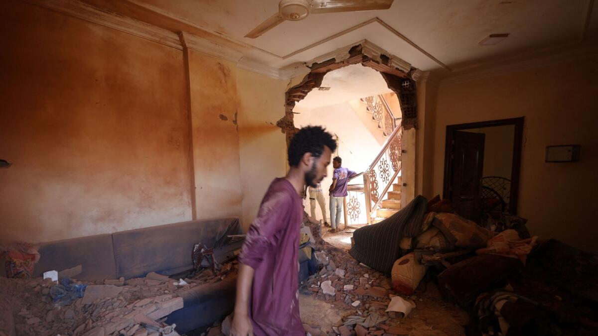 A man looks at the damage inside a house during clashes. — Reuters