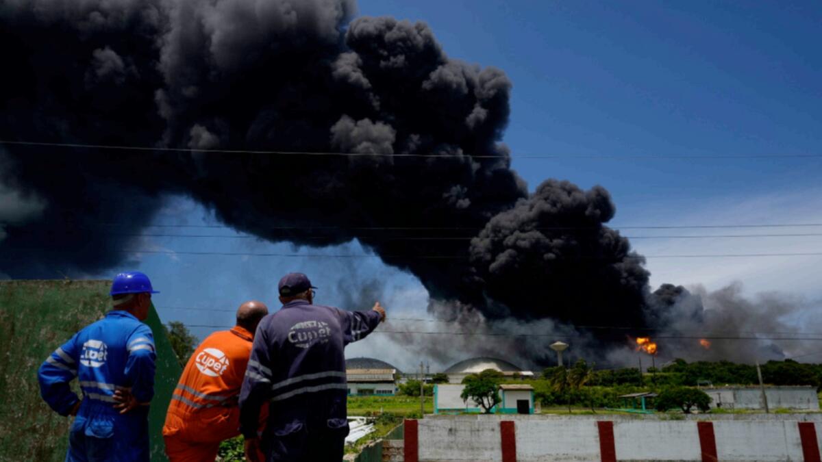 Workers of the Cuba Oil Union watch a huge rising plume of smoke from the Matanzas Supertanker Base. — AP