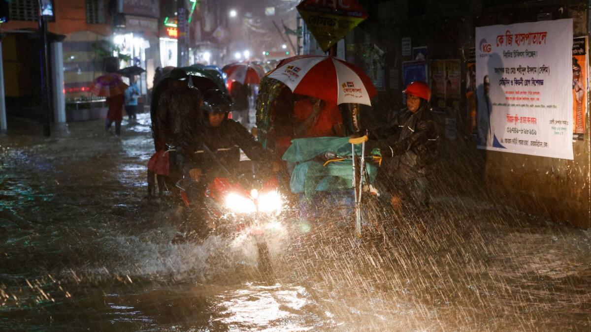People ride rickshaws and motorcycle on a flooded street, amid continuous rain before the Cyclone Sitrang hits the country in Dhaka, Bangladesh. — Reuters