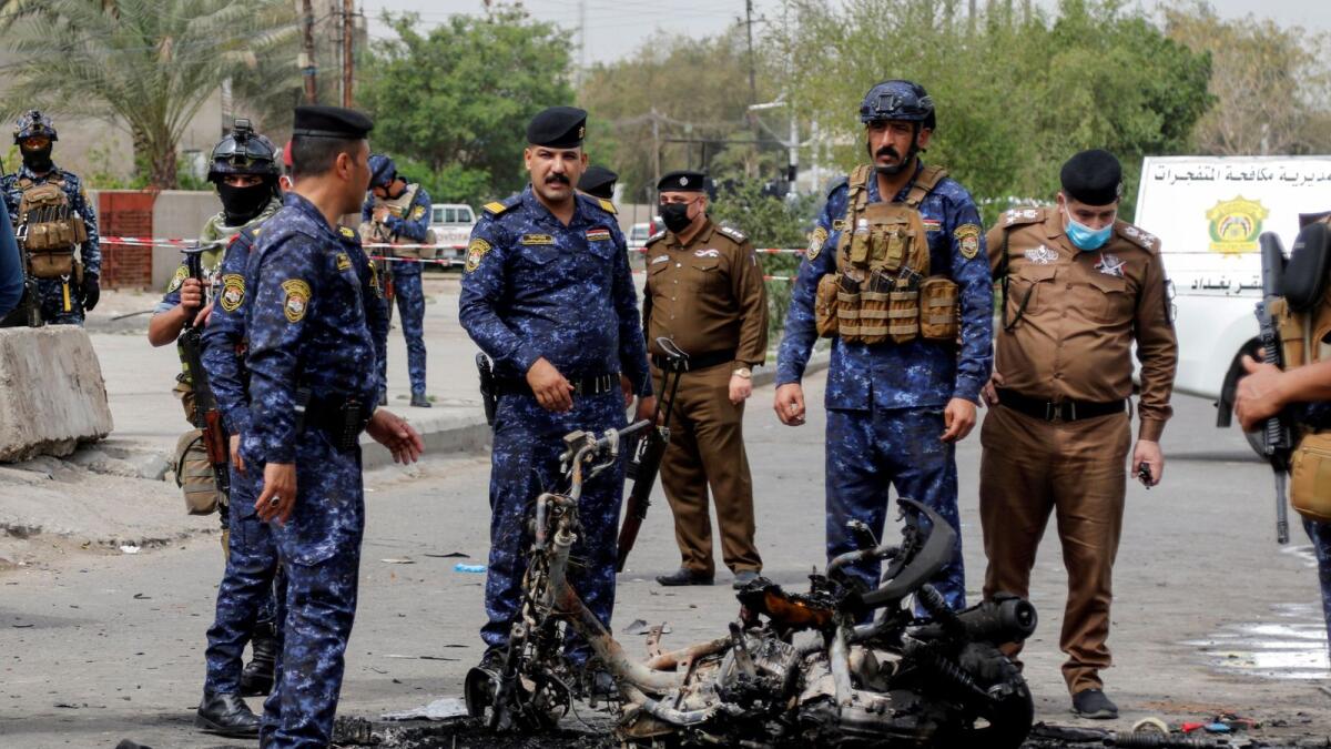Members of security forces inspect the scene of an explosion in Baghdad on March 23, 2021.
