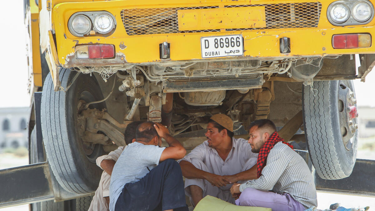 Truck drivers resting under a heavy truck on a hot day in Dubai.- Photo by Shihab/ Khaleej Times