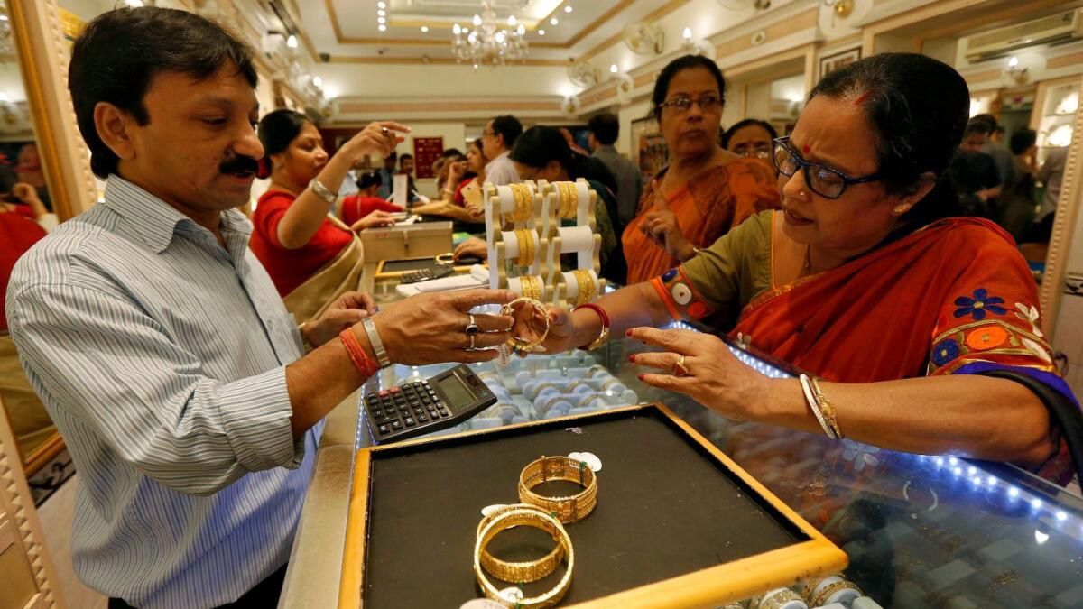 A salesman shows gold bangles to a customer at a jewellery showroom in Kolkata. -- Reuters file photo