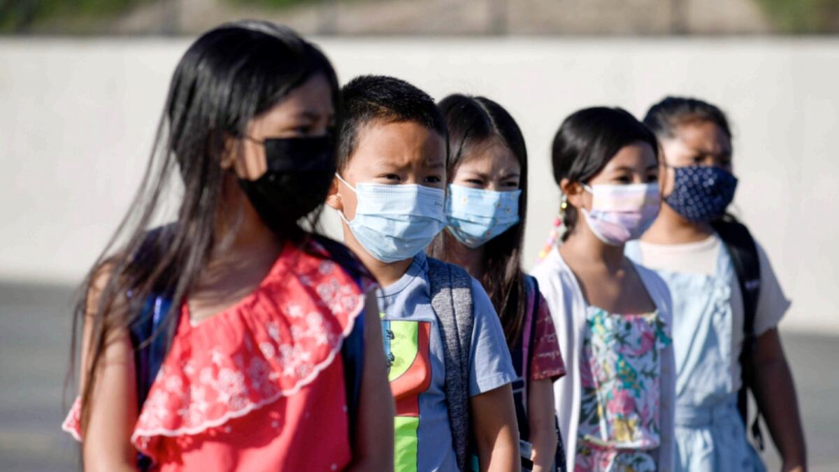 Masked students wait to be taken to their classrooms at an elementary school in California. — AP