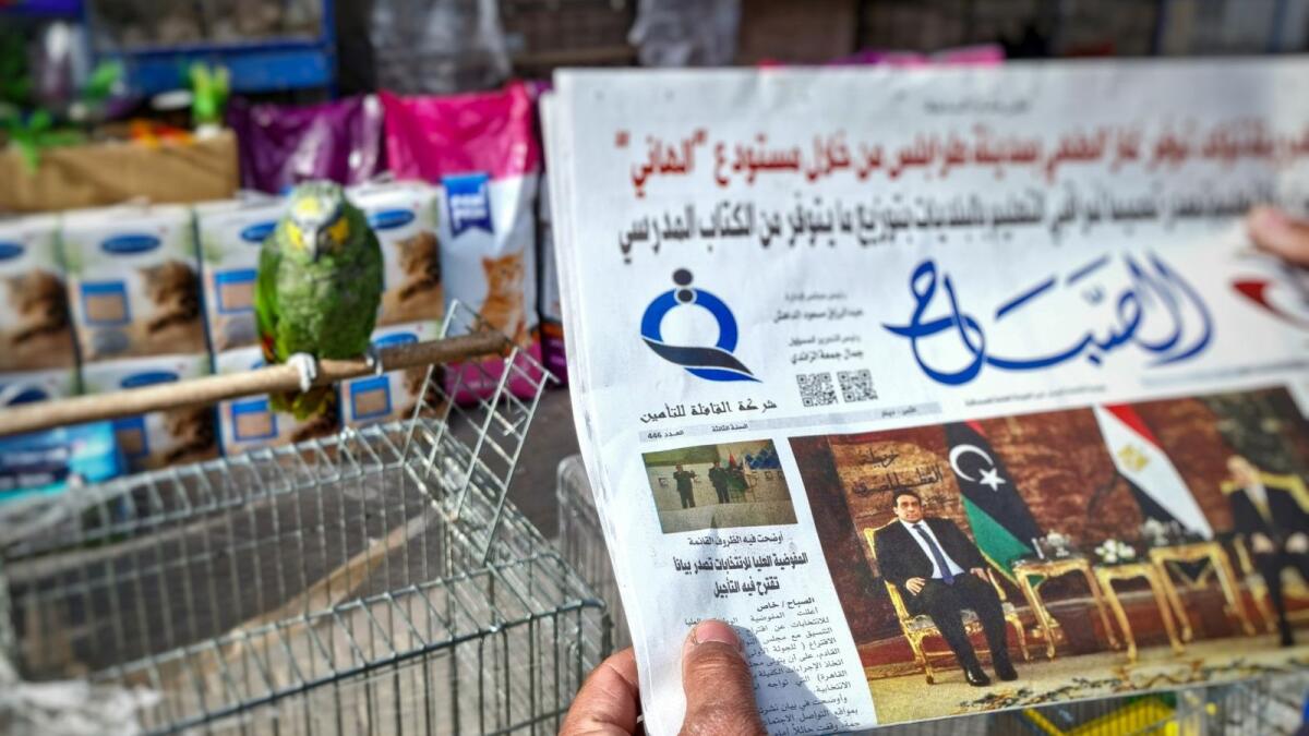 A man reads a local newspaper in the Libyan capital Tripoli, on December 23, 2021, with an article on its front page about the postponement of the country's presidential elections. — AFP