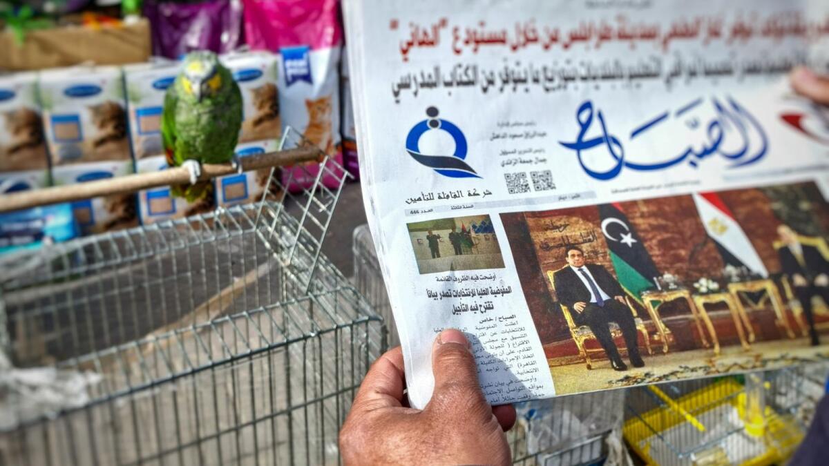 A man reads a local newspaper in the Libyan capital Tripoli, on December 23, 2021, with an article on its front page about the postponement of the country's presidential elections. — AFP