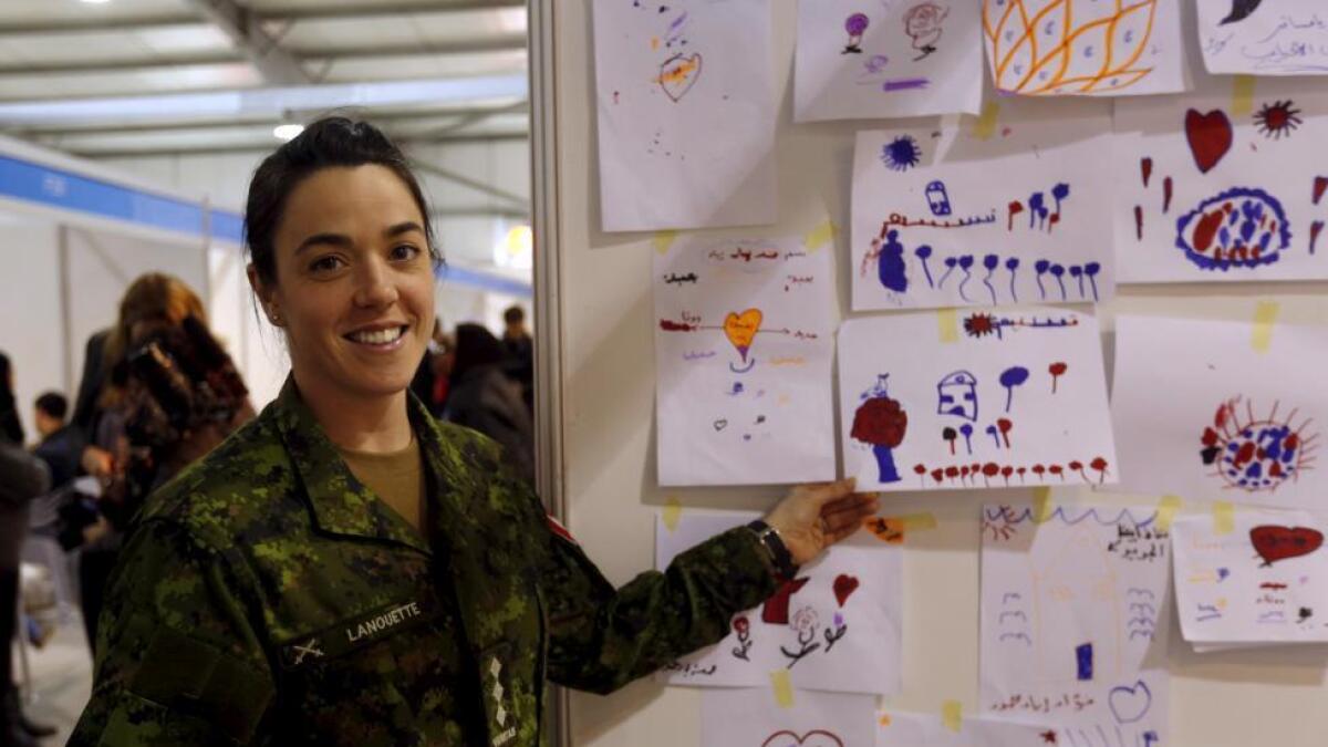 A Canadian army officer poses next to drawings by Syrian refugee children at the Canadian processing center for Syrian refugees, during a media tour held by the Canadian Embassy in Jordan, at Marka airport, Amman, Jordan.
