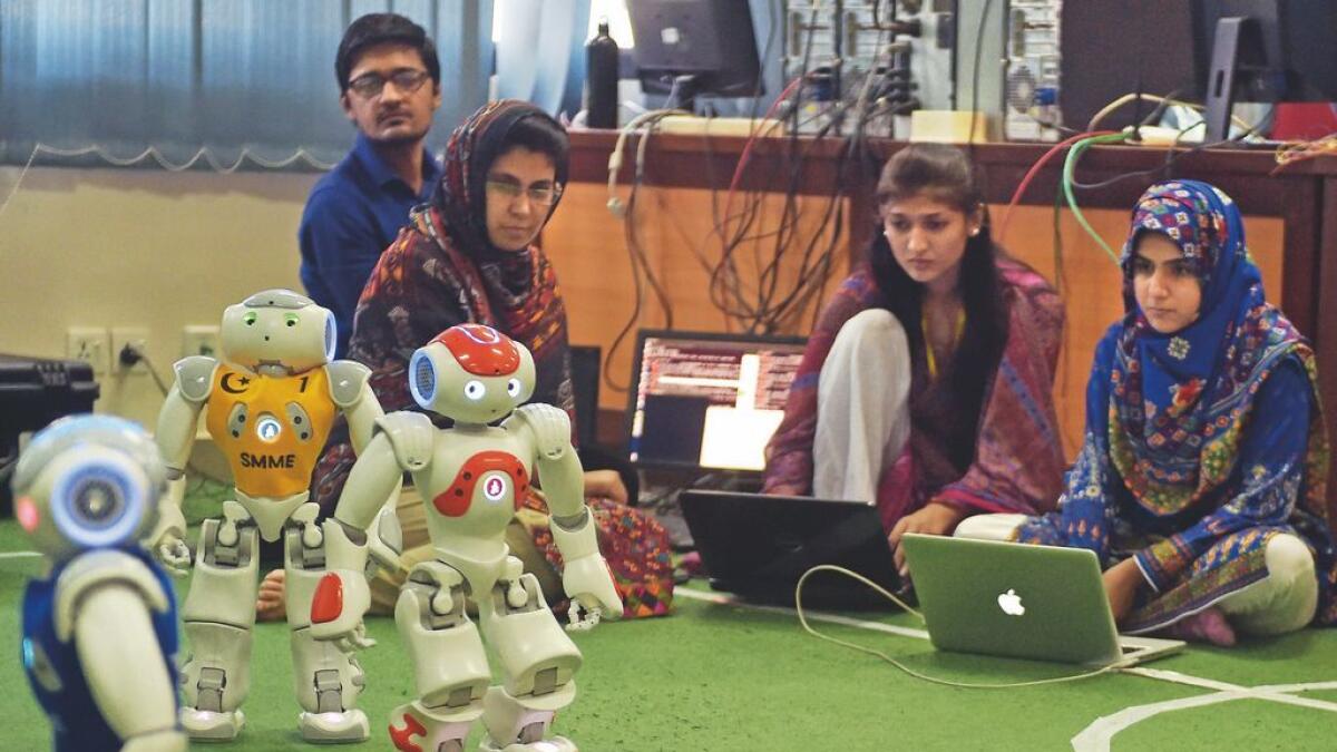 Students and members of Robotics and Intelligence Systems Engineering (RISE) watch their robots play a football match at the engineering department of the National University of Sciences and Technology in Islamabad.