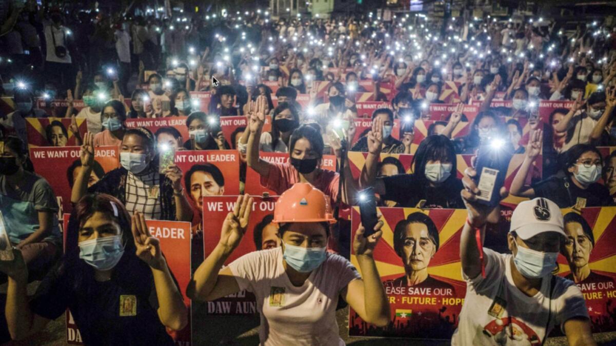 Protesters hold up the three-finger salute and placards with the image of detained Myanmar civilian leader Aung San Suu Kyi while using their mobile torches during a demonstration against the military coup in Yangon. — AFP file