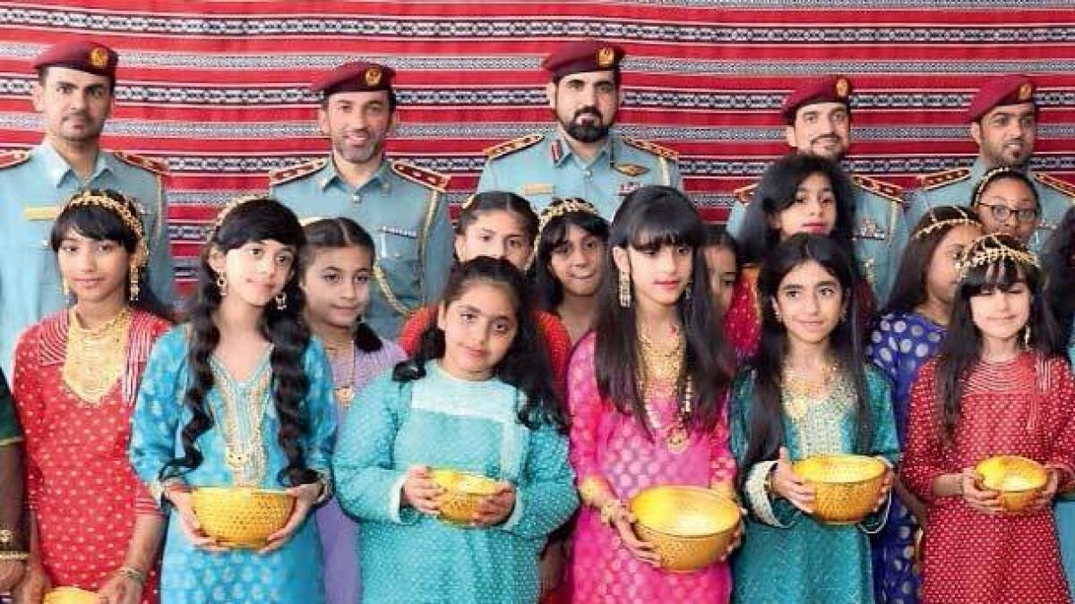 All dressed up, children of RAK prisons’ staff members and inmates  hold up their bowl of Hag Al Laila sweets. — Supplied photo