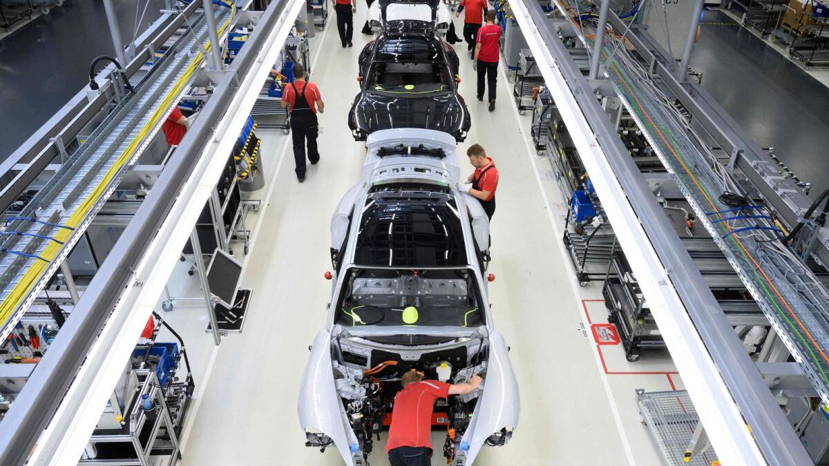 Employees of German car producer Porsche AG work on Porsche Taycan electric sports cars at the assembly line of the Porsche production site in Stuttgart, southwestern Germany. — AFP file