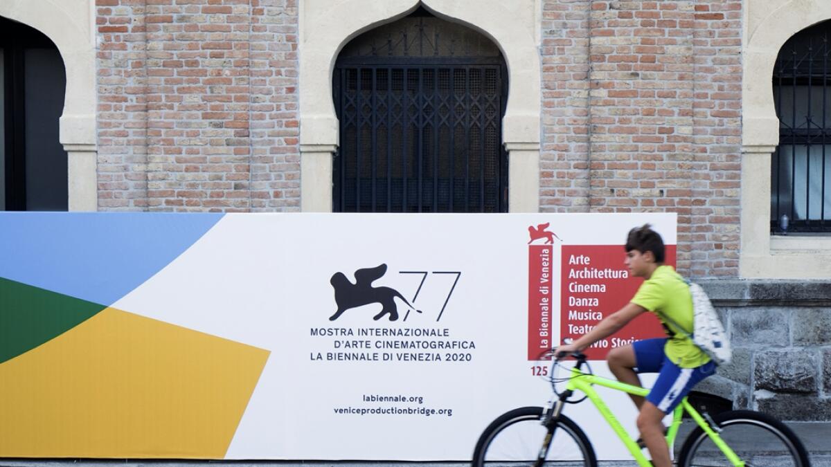 A boy rides a bike next to a logo of the 77th Venice Film Festival, the first major international film festival held since the coronavirus disease (Covid-19) outbreak, in Venice, Italy. Photo: Reuters