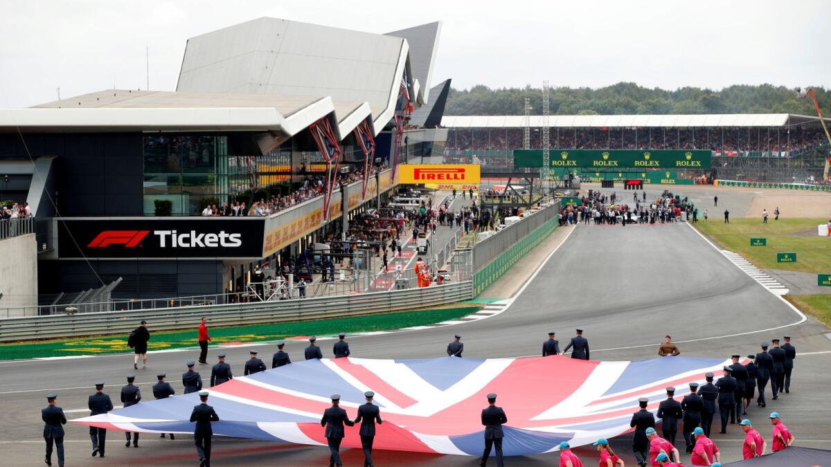 General view of a Union Jack flag being carried out on to the track by service personnel. — Reuters