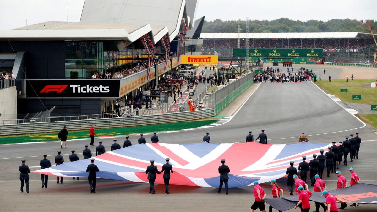 General view of a Union Jack flag being carried out on to the track by service personnel. — Reuters