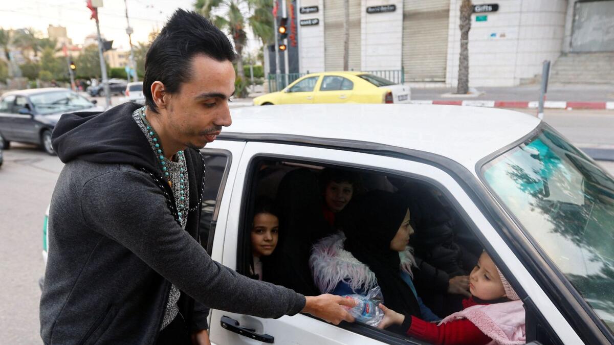 A Palestinian Christian man Ehab Ayyad offers dates and water to Muslims held up in traffic or getting late for home to end their fast in Gaza City on Wednesday. — Reuters