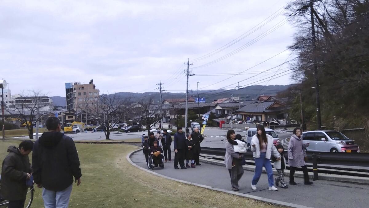 People walk to a higher place to take shelter after an earthquake in Wajima. — AP