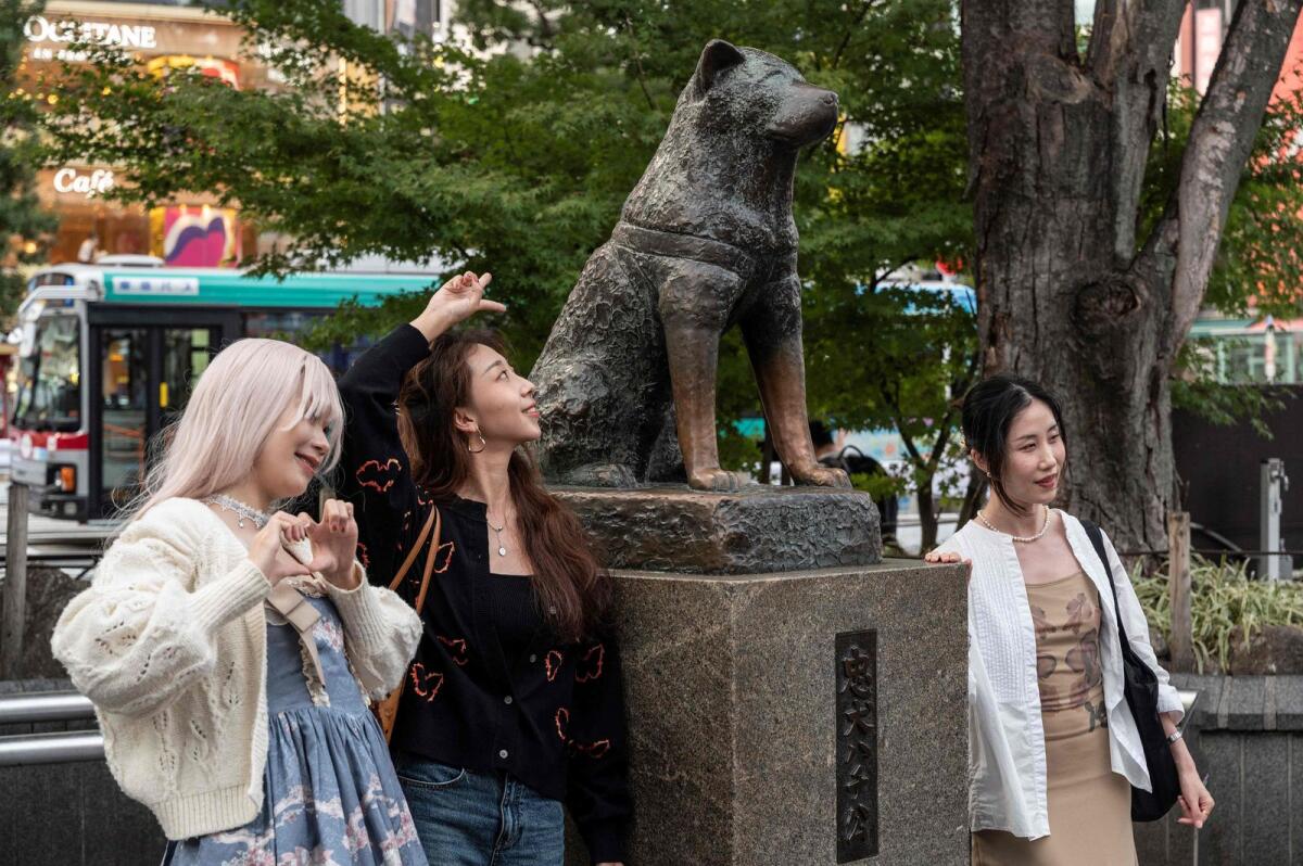 People posing for photos next to the statue of 'Hachiko' in front of Shibuya station in central Tokyo ahead of the 100th anniversary of the legendary dog's birth this month. — AFP