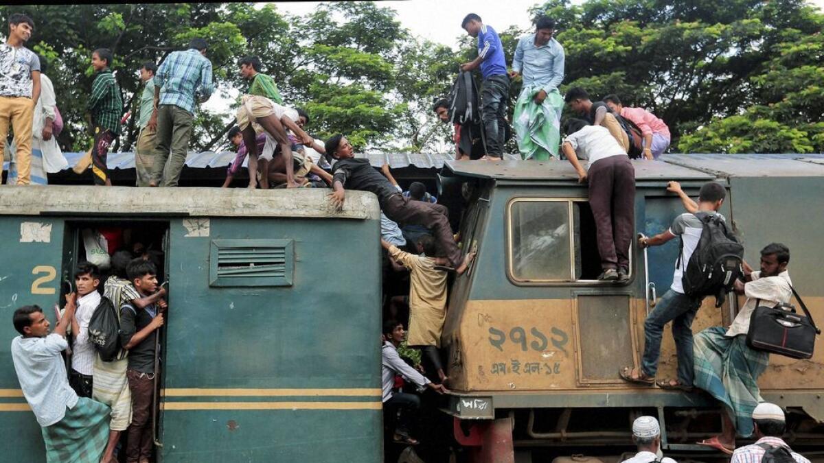 Bangladeshi passengers try to climb on to the roof of an overcrowded train as they head home ahead of Eid al-Fitr at a railway station in Dhaka, Bangladesh