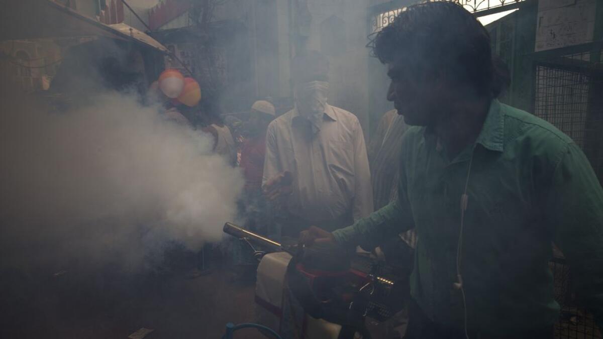 A municipality worker uses a machine to fog for mosquitoes at a neighborhood in New Delhi, India. 