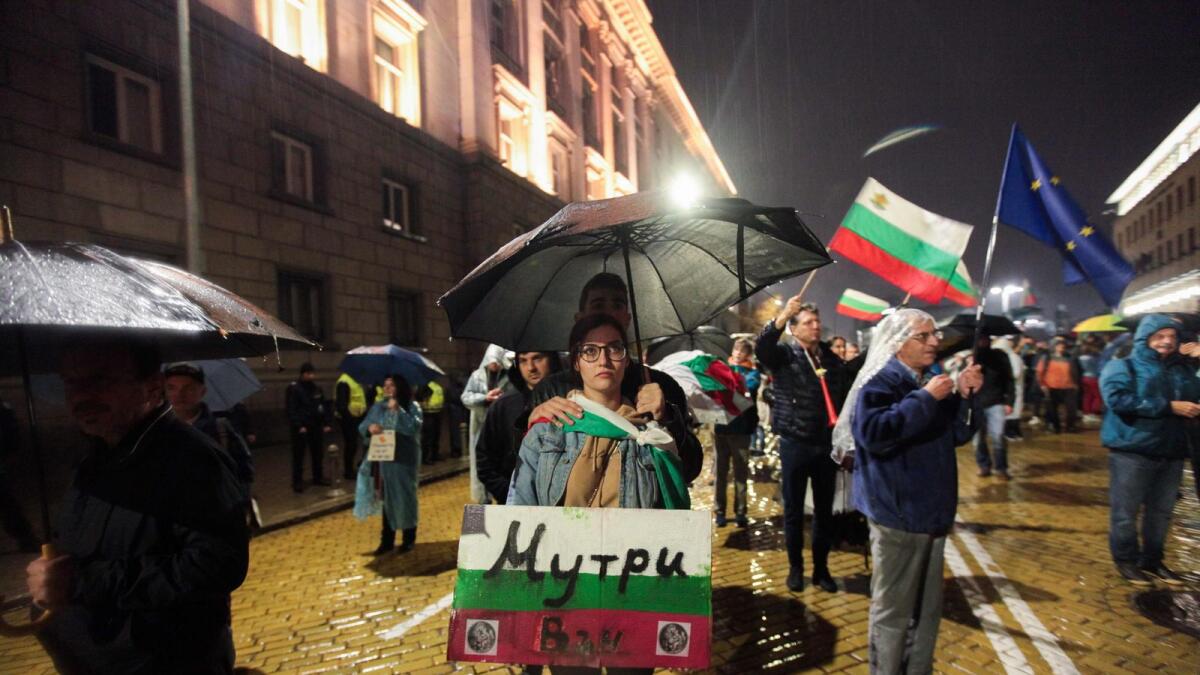 A couple holds a placard with the Bulgarian flags and sign reading in Bulgarian 'thugs out' during an anti-government protest near the parliament building in Sofia.