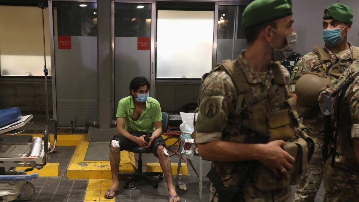 An injured man sits outside American University of Beirut (AUB) medical centre following an explosion in Beirut. Reuters