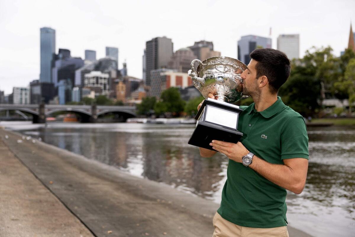 Novak Djokovic kisses the trophy with the Yarra River and the Melbourne skyline in the background. — AFP