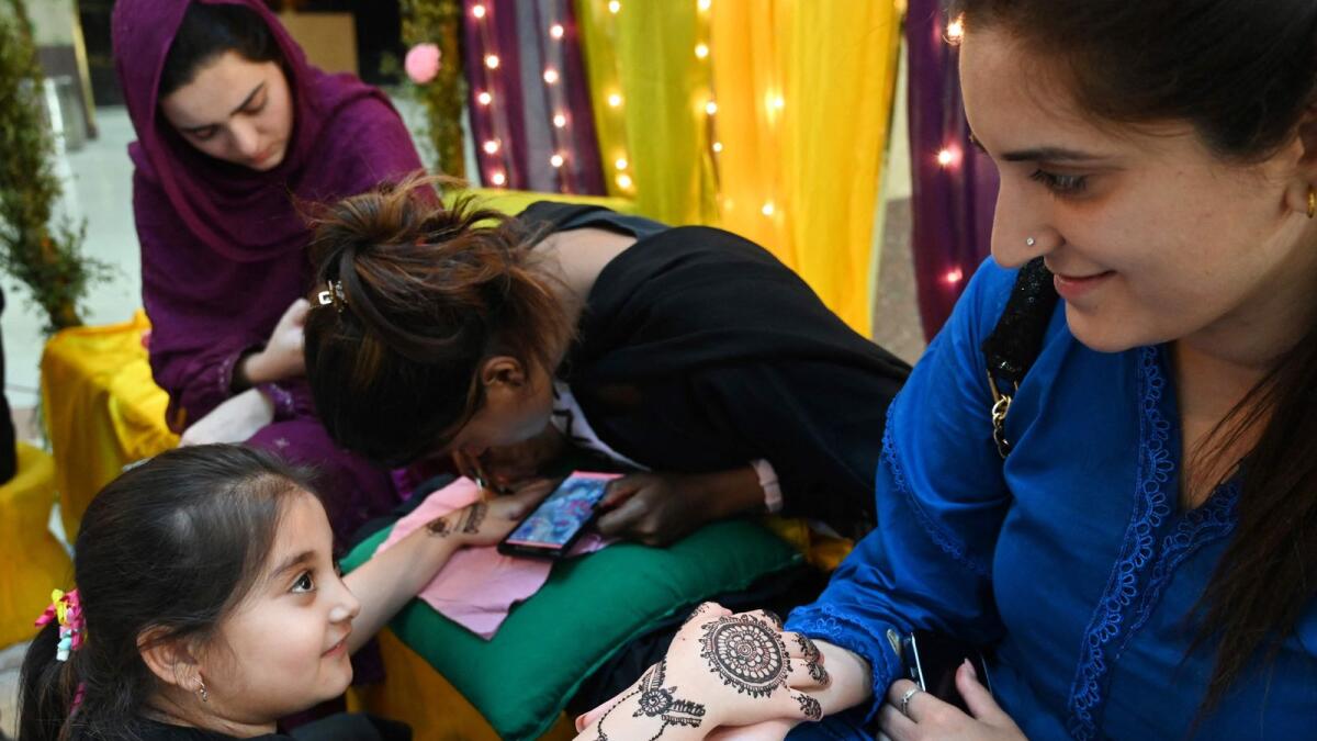 A beautician applies a 'henna' design on a customer's hand at at a mall ahead of Eid Al Fitr festival in Islamabad on Friday. — AFP