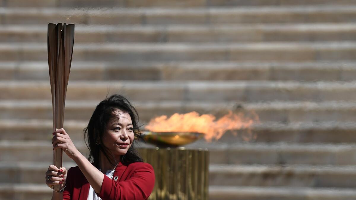 Former Japanese swimmer Imoto Naoko holds the Olympic torch during the Olympic flame handover ceremony for the Tokyo Summer Olympics, in Athens on March 19, 2020. The ceremony was held behind closed doors and with the presence of few members of the media because of fears over the coronavirus. (AP file)