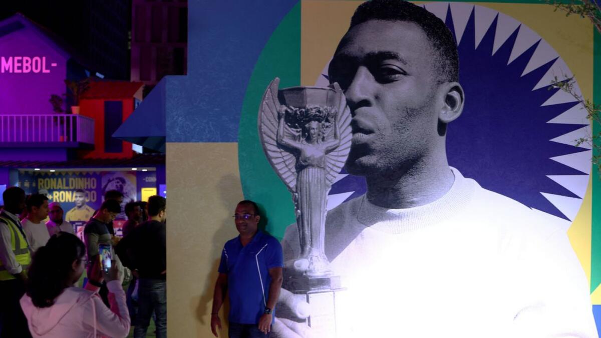 A fan poses in front of a picture of Brazil's Pele at CONMEBOL - Tree of Dreams exhibition: Reuters