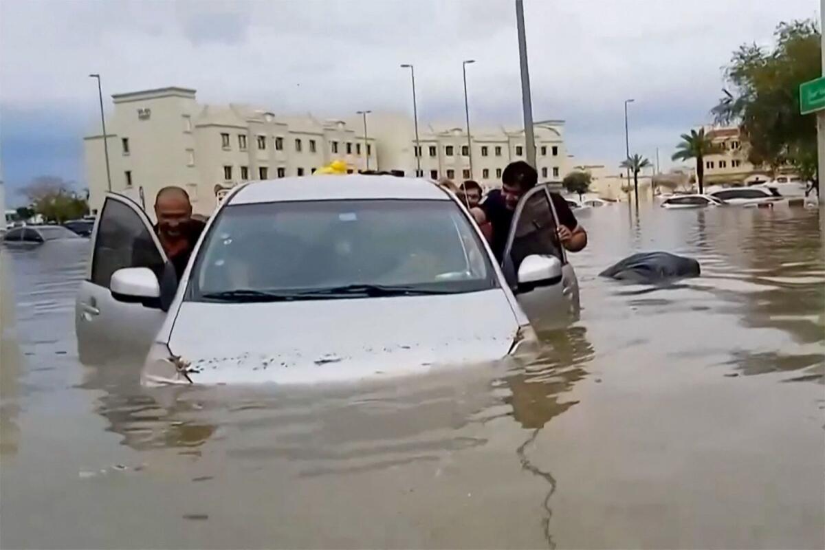 People push a stranded car along a flooded street in Dubai on April 16, 2024. Photo: AFP