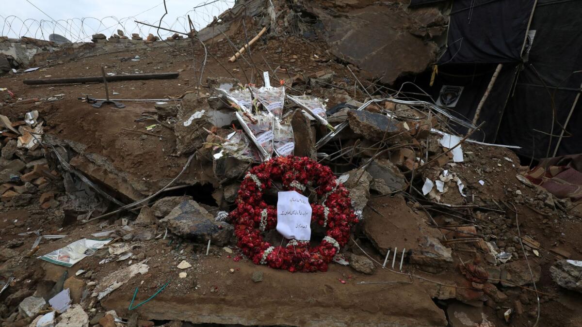 A wreath and bouquets of flowers sit on top of debris from the mosque that was attacked by a suicide bomber in January in the Police Lines area in Peshawar. — Reuters file