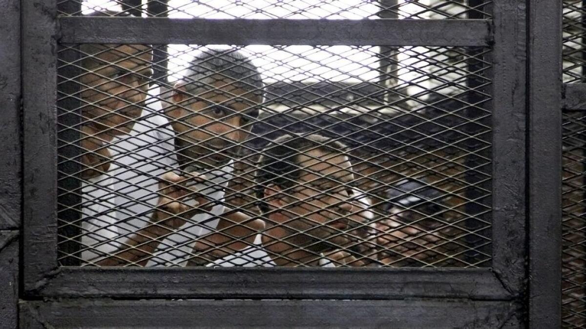 From left, Australian correspondent Peter Greste, Canadian-Egyptian acting bureau chief of Al Jazeera Mohamed Fahmy, and Egyptian producer Baher Mohammed, appear in a defendants cage in a courtroom in Cairo, Egypt.