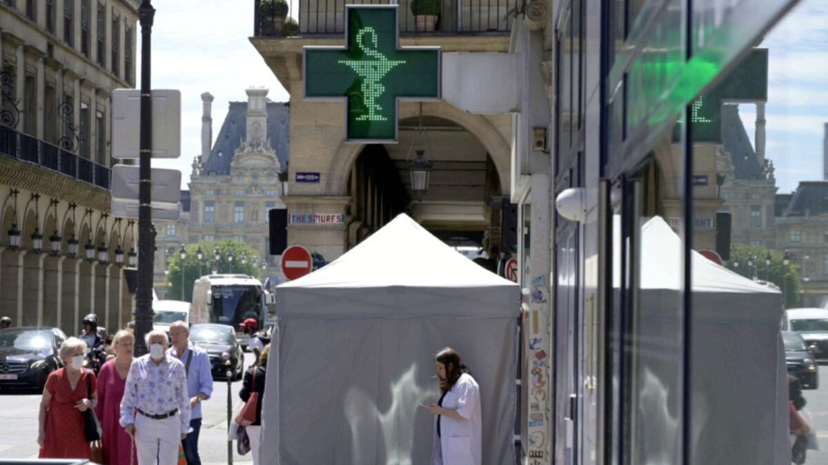 A medical staff smokes near a curbside testing tent placed in front of a pharmacy, in Paris. — AFP