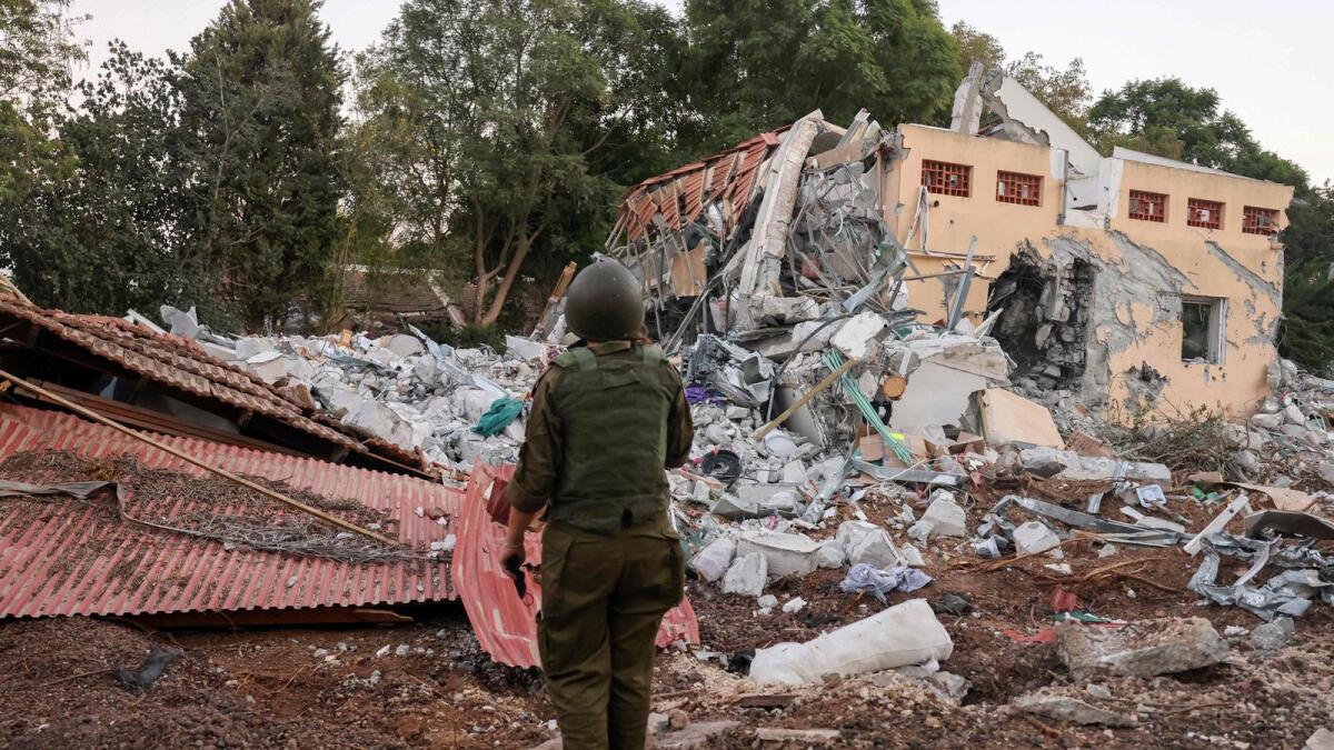 An Israeli soldier stands in front of a destroyed house at the scene of last weekend's inflitration by Palestian militants on Kibbutz Beeri near the border with Gaza. — AFP