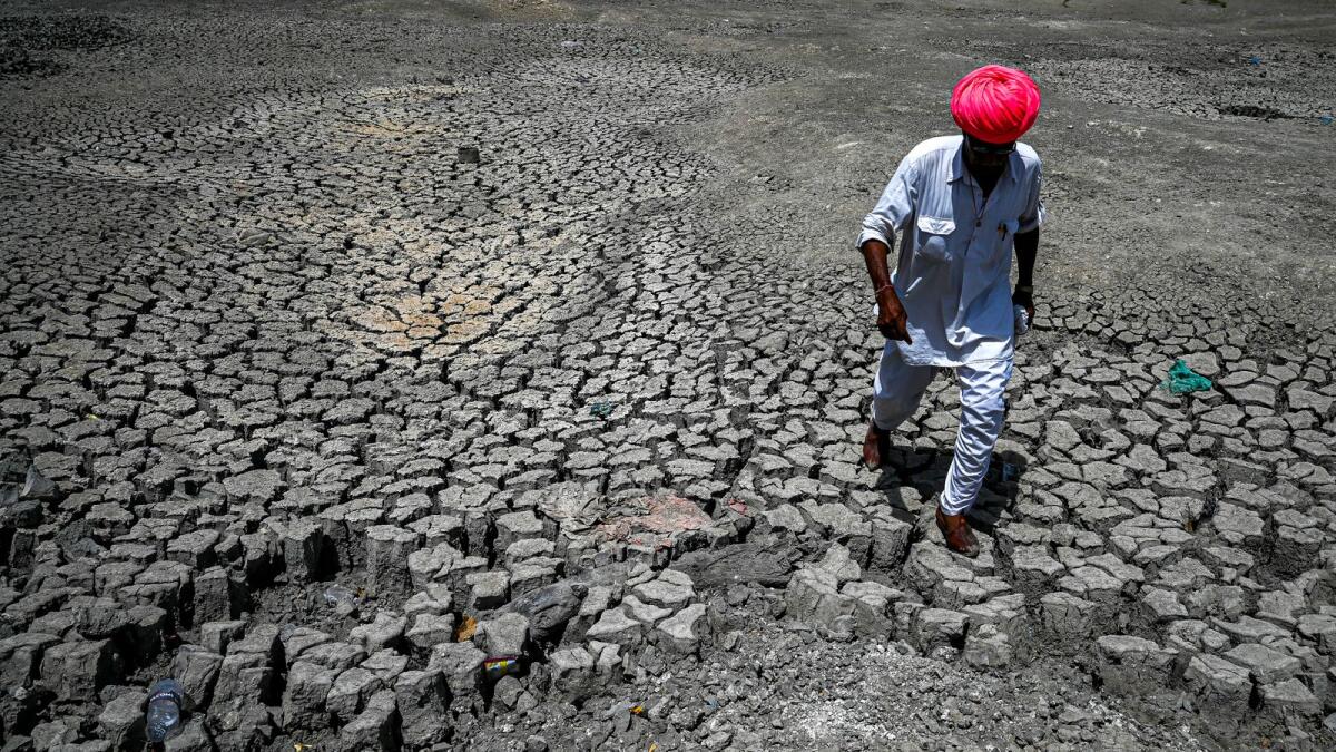 A villager walking through the cracked bottom of a dried-out pond in Rajasthan. — AFP file