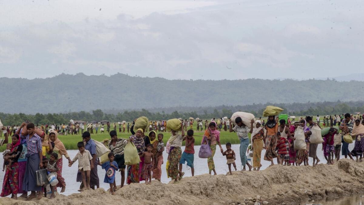 Rohingya Muslims, who spent four days in the open after crossing over from Myanmar into Bangladesh, carry their belongings after they were allowed to proceed towards a refugee camp, at Palong Khali, Bangladesh,  on October 19, 2017. — AP