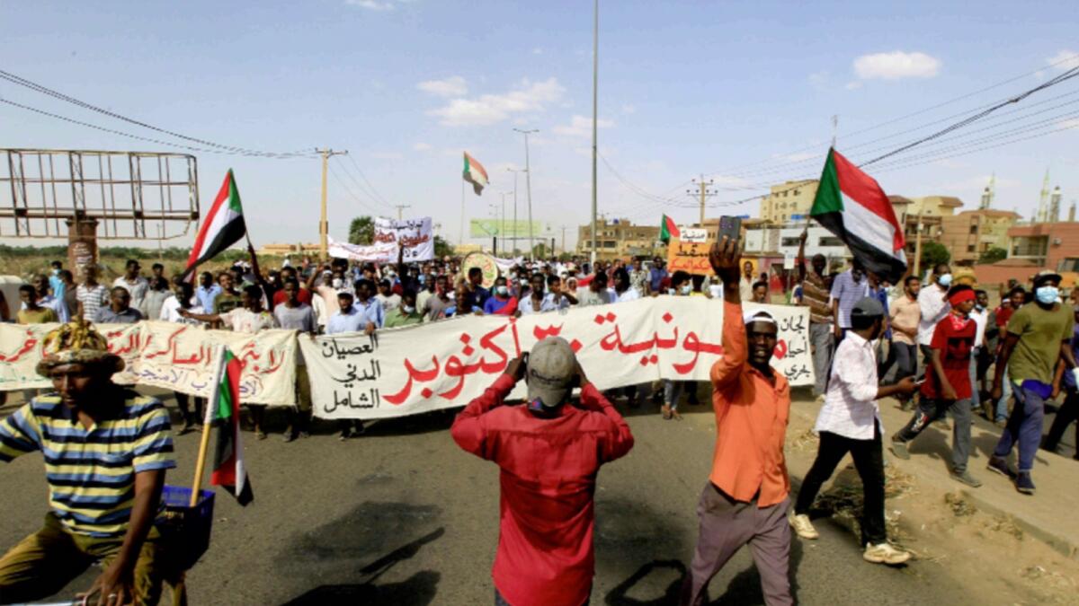 Protesters carry a banner and national flags in a march against Sudan's military coup. — AP
