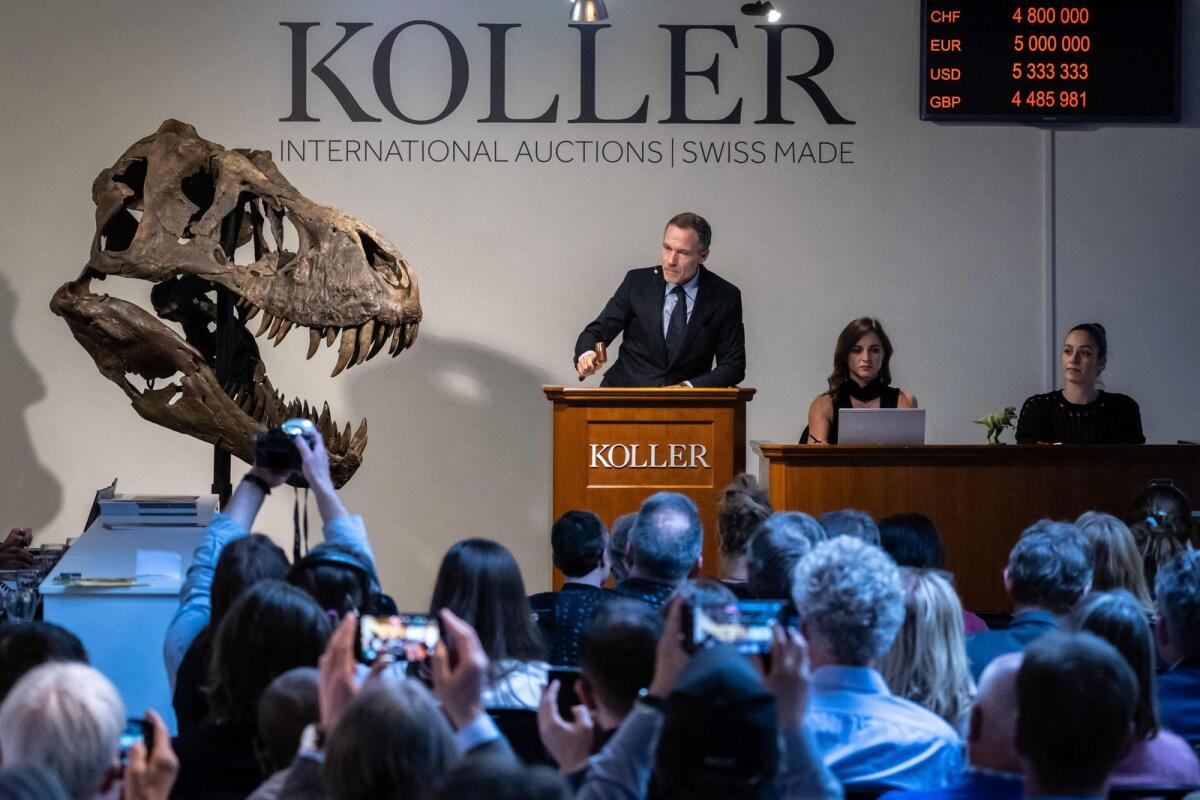 Koller auction house director Cyril Koller (C) gestures next to the skull of the 'Trinity' during sale of the skeleton of the Tyrannosaurus-Rex (T-Rex) by Koller auction house in Zurich on Tuesday. — AFP