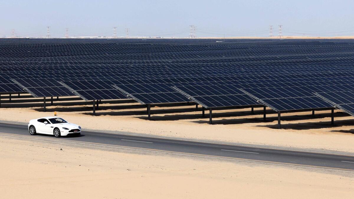 A car drives next to photovoltaic panels at Al Dhafra Solar Photovoltaic (PV) Independent Power Producer (IPP) project south of Abu Dhabi. Photo: AFP file