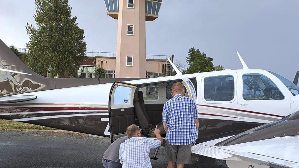 People look inside a plane at the Welkom Airport as they search for a venomous snake that the pilot found hiding under his seat midair, on Monday. — AP