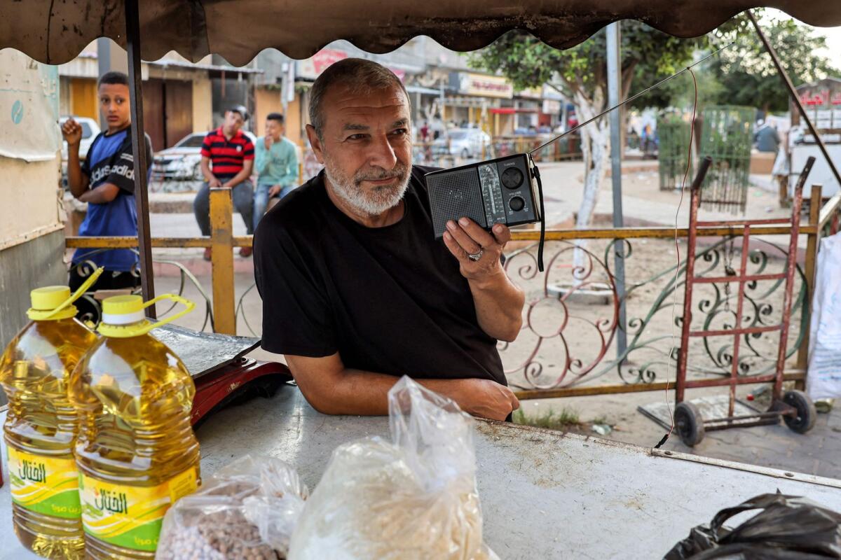 A man holds a portable radio reciever as he listens to a news broadcast along a street in Rafah in the southern Gaza Strip on October 31. — AFP