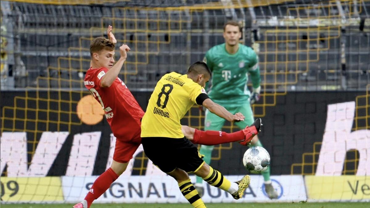 Borussia Dortmund's Mahmoud Dahoud take a shot as Bayern Munich's Joshua Kimmich tries to stop him during their Bundesliga match on Tuesday. - Reuters