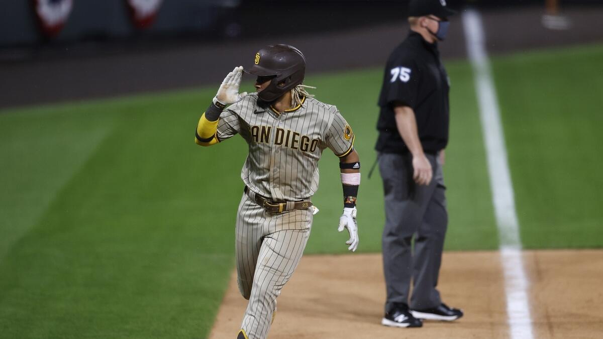 San Diego Padres' Fernando Tatis Jr. salutes his dugout as he circles the bases after hitting a solo home run off Colorado Rockies relief pitcher Wade Davis in the ninth inning of a baseball game on Friday