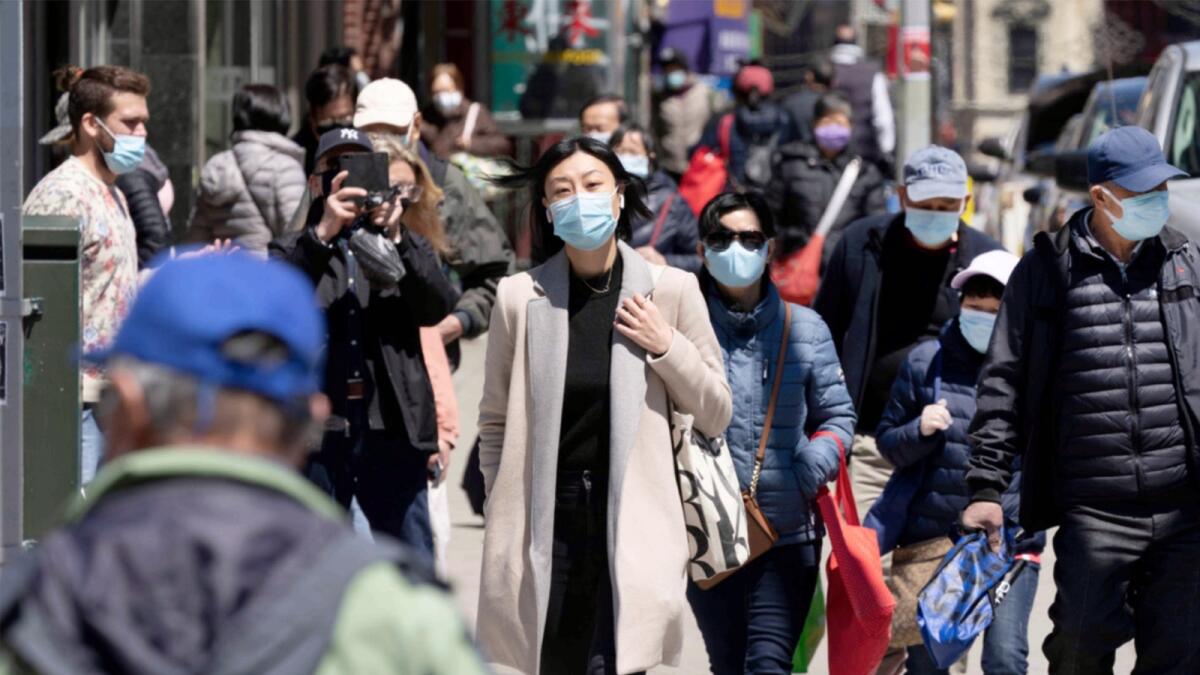 People wearing face masks walk on a New York street. — AP